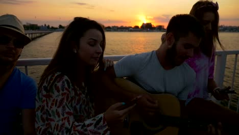 Friends-singing-on-summer-time-with-a-guitar-on-a-bridge-in-slow-motion