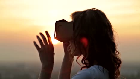 Woman-uses-a-virtual-reality-glasses-at-sunset