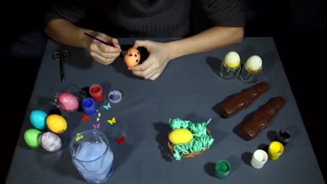 Female-hands-painting-the-egg-decoration-for-easter-over-a-gray-background.