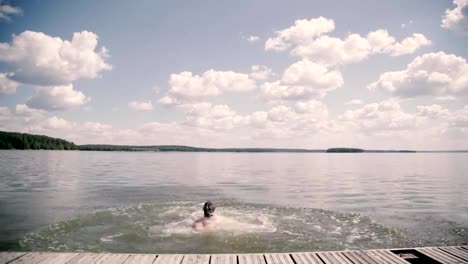 Overweight-guy-dives-on-the-pier-in-a-lake-summer