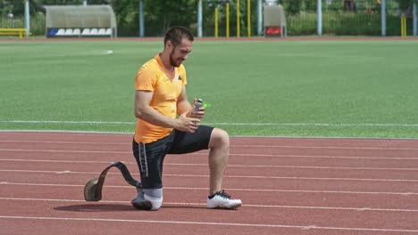 Amputierter-Athlet-gießen-Wasser-auf-Kopf-während-des-Trainings-am-Stadion