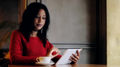 Woman-using-tablet-pc-drinking-coffee-in-cafe