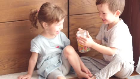 niedlichen-Kinder-spielen-mit-Glas-mit-Süßigkeiten