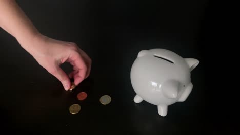 Woman-putting-Euro-coins-into-a-piggy-bank