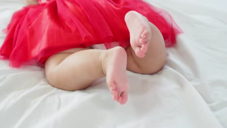 Baby-girl-lying-on-her-stomach-and-swing-her-legs-to-try-to-crawl-in-slow-motion-shot