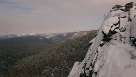 Aerial-view-of-a-rock-climber-climbing-a-steep-cliffs-during-a-sunny-winter-day.