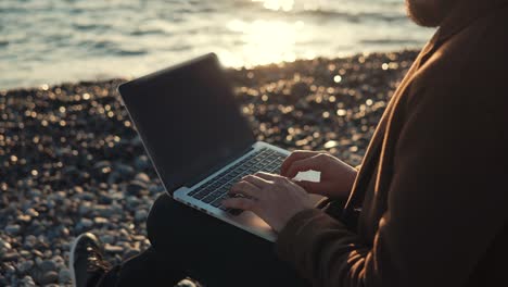 Modern-writer-is-typing-on-keyboard-of-notebook-in-background-of-sea-tide