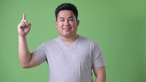 Young-handsome-overweight-Asian-man-against-green-background