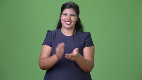 Young-overweight-beautiful-Indian-businesswoman-against-green-background