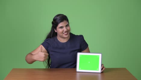 Young-overweight-beautiful-Indian-businesswoman-against-green-background