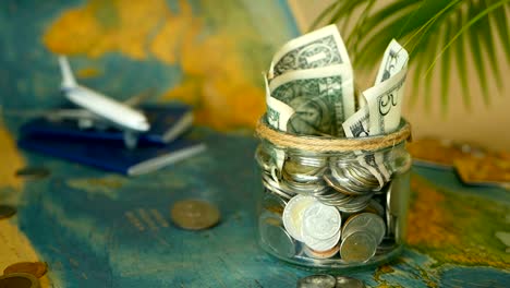 Travel-budget-concept.-Money-saved-for-vacation-in-glass-jar-on-world-map-background