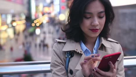 Joven-mujer-asiática-usando-teléfono-inteligente-en-la-ciudad