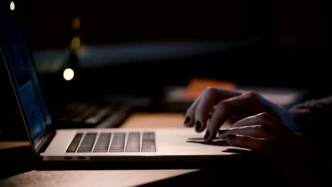 Close-up-female-fingers-on-laptop-touchpad.-Girl-surfing-the-web-in-the-dark.-Shopping-online.-Working-from-home.-4K