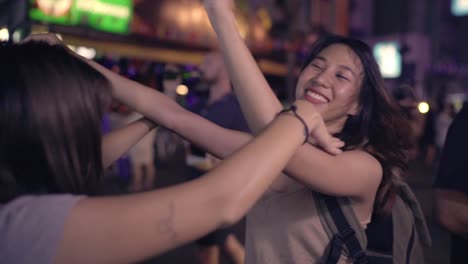 Slow-Motion---Reisende-Backpacker-asiatische-Frauen-Lesben-LGBT-Paare-tanzen-zusammen.-Weibliche-Alkohol-oder-Bier-mit-Freunden-trinken-und-feiern-auf-der-Khao-San-Road-in-Bangkok,-Thailand.