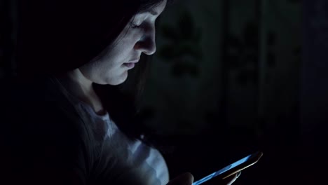 Young-woman-sitting-at-night-with-phone-in-social-networks