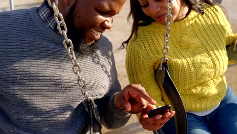 Happy-couple-using-mobile-phone-in-the-park-on-a-sunny-day-4k