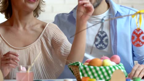 Frau-und-Mann-Verschönerung-Äste-eines-Baumes-mit-dekorativen-Ostereier,-Fest