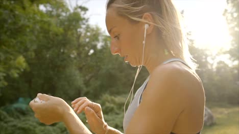 Young-woman-jogging-outdoors-using-mobile-phone-app-choosing-music-for-morning-training-in-forest-path.-People-healthy-lifestyle-concept---Slow-motion