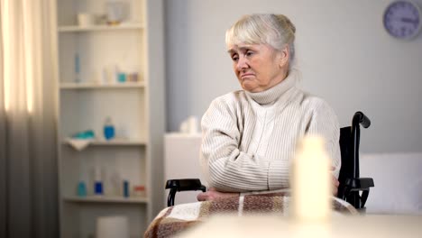 Deprimida-mujer-en-silla-de-ruedas-mirando-en-píldoras-y-pensando-en-diagnóstico