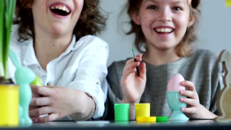 Cerca-de-retrato-de-un-niño-y-una-niña-con-pinturas-y-pinceles.-Creatividad-de-Pascua-infantil.-Hermano-y-hermana-decoran-huevos-de-Pascua-y-reír-alegremente