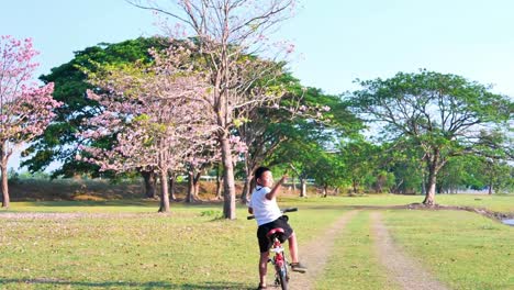 An-Asian-woman-jogging-in-natural-sunlight-in-the-evening,-along-with-his-son-riding-a-bicycle.--exercising-for-good-health.