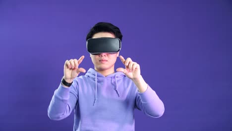 Young-Asian-man-playing-VR-game-in-dark-blue-background.-Chinese-young-hipster-wearing-VR-headset