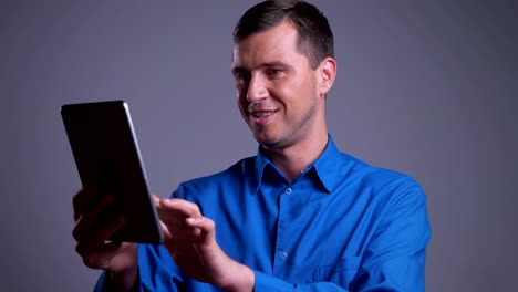 Closeup-portrait-of-adult-happy-caucasian-man-tapping-on-the-tablet-and-smiling-in-front-of-the-camera