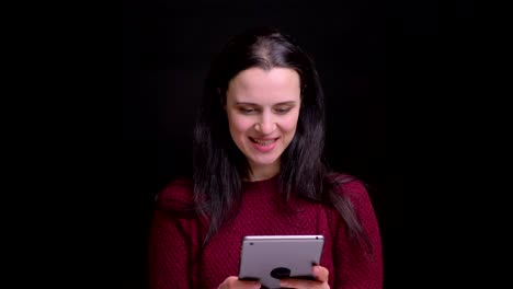 Closeup-portrait-of-young-caucasian-female-with-black-hair-using-the-tablet-and-laughing-with-excitement