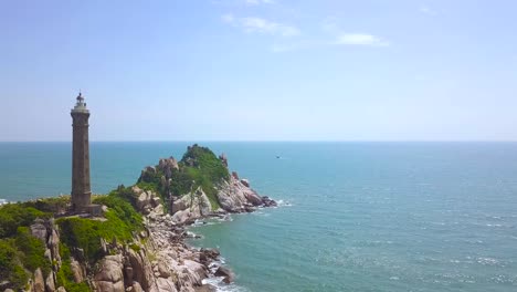 Lighthouse-on-rocky-island-in-blue-sea-aerial-landscape.-Drone-view-light-house-on-cliff-in-ocean-on-blue-water-and-sky-background