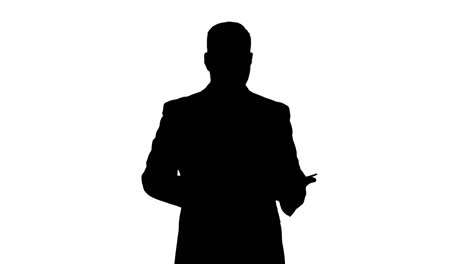 Silhouette-Businessman-walking-and-swiping-pages-on-his-tablet-computer-and-looking-to-camera-presenting-something