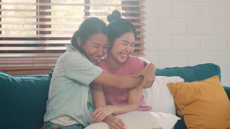 Young-Asian-Lesbian-couple-hug-and-kiss-lying-sofa-in-living-room-at-home.