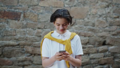 Joyful-teenage-boy-using-smartphone-in-the-street-smiling-having-fun-with-gadget