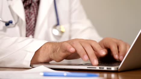 Physician-introducing-patient-medical-data-on-laptop-and-talking-on-mobile-phone,-close-up