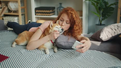 Mujer-amorosa-besando-cachorro-lindo-y-tomar-selfie-con-el-teléfono-inteligente-en-el-sofá