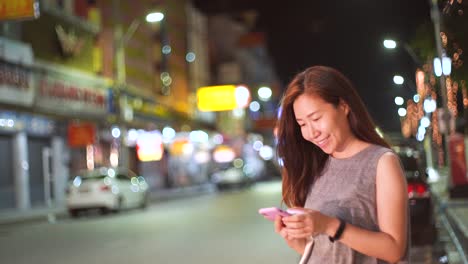 Junge-asiatische-Frau-mit-Smartphone-in-der-Straße-in-der-Nacht,-Lifestyle-Konzept