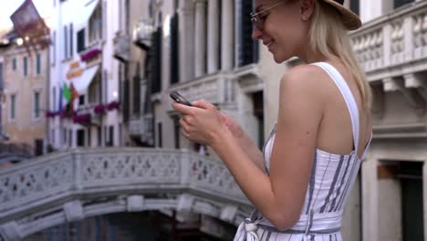 Chica-hipster-sonrisa-feliz-vestida-con-un-aspecto-elegante-buscando-información-sobre-las-visitas-turísticas-en-Venecia