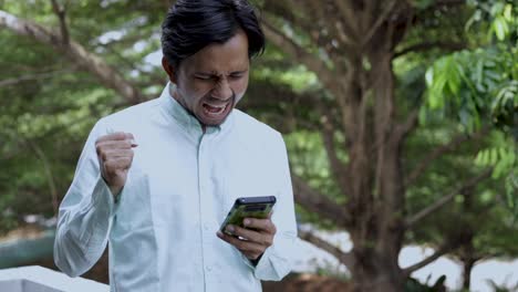 Excited-Man-asian-Enjoying-Success-while-Using-Smartphone