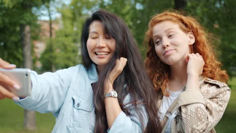 Attraktive-junge-Frauen-machen-Selfie-im-Freien-im-Park-berührende-Haare-lächelnd