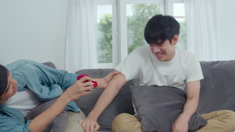 Young-Asian-gay-couple-propose-at-home,-Teen-korean-LGBTQ-men-happy-smiling-have-romantic-time-while-proposing-and-marriage-surprise-wear-wedding-ring-in-living-room-at-house-concept.