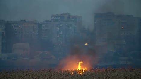 Impresionante-vista-de-los-bloques-de-apartamentos-modernos-en-la-orilla-del-río-Dnipro-y-el-fuego-brillante-a-través-del-río-en-el-pantano-de-caña-en-primavera