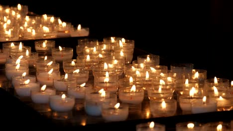 Religious-view-of-numerous-outdoor-candles-lit-in-a-Catholic-Christian-church-in-Bruges-in-slow-motion.-They-look-beautiful-and-eternal.