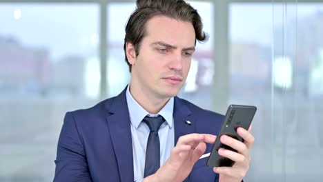 Portrait-of-Relaxed-Young-Businessman-using-Smartphone