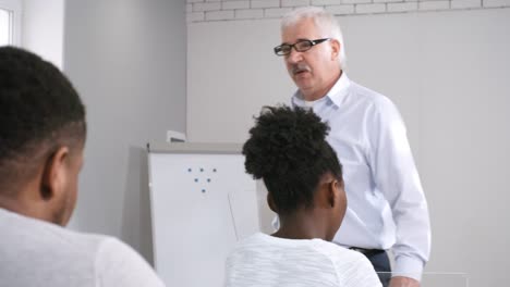 Strenger-männlicher-Professor-spricht-mit-AR-Geräten-zu-Klasse-von-College-Studenten