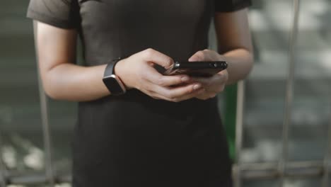 Close-up-asian-girl-athlete-running-using-smartphone-sharing-messages-on-social-media-communication-while-standing-beside-on-the-street-urban.