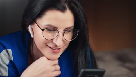 Woman-in-wireless-earphones-talking-on-video-call-use-smartphone.-Close-up-shot-on-4k-RED-camera