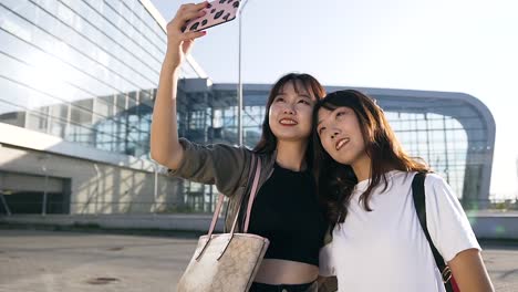 Slow-motion-of-exuberant-cute-asian-female-mates-making-selfie-on-the-airport-background