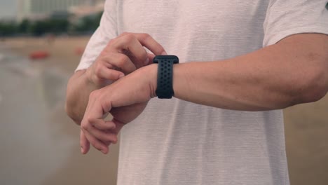 Nahaufnahme-asiatischen-Sport-Läufer-Überprüfen-Herzfrequenz-auf-Smartwatch-nach-dem-Laufen-während-des-Stehens-am-Strand-während-eines-schönen-Sonnenuntergangs-im-Sommer.