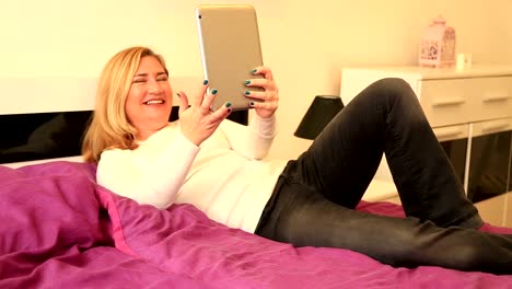 Woman-Talking-Via-Internet-With-Tablet-At-The-Bedroom