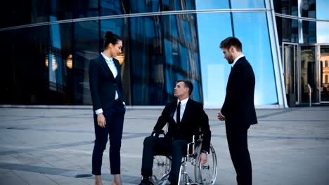 Disabled-businessman-in-wheelchair-and-two-his-collegues-has-positive-conversation