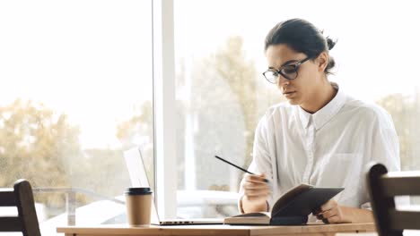 Mujer-de-escribir-y-hacer-anotaciones-en-el-café